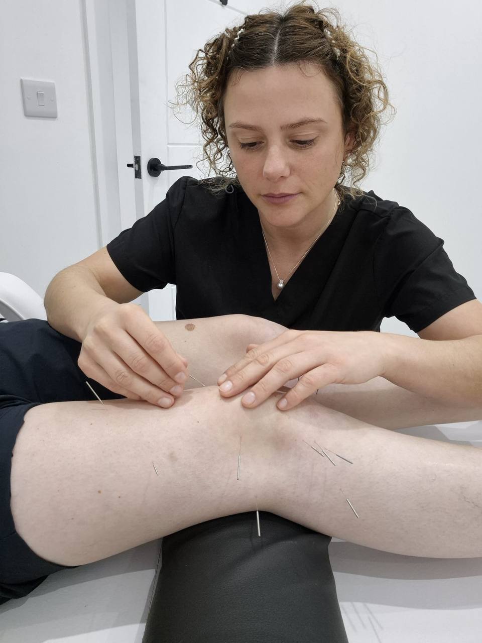 Maxine placing acupuncture needles during a knee treatment